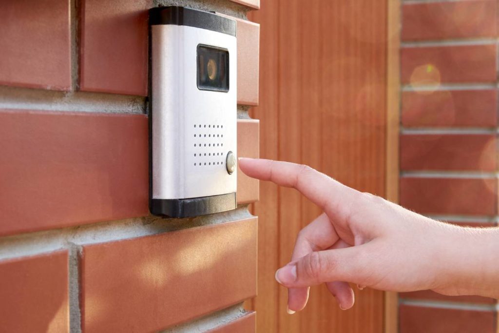 The female hand presses a button doorbell with camera and intercom